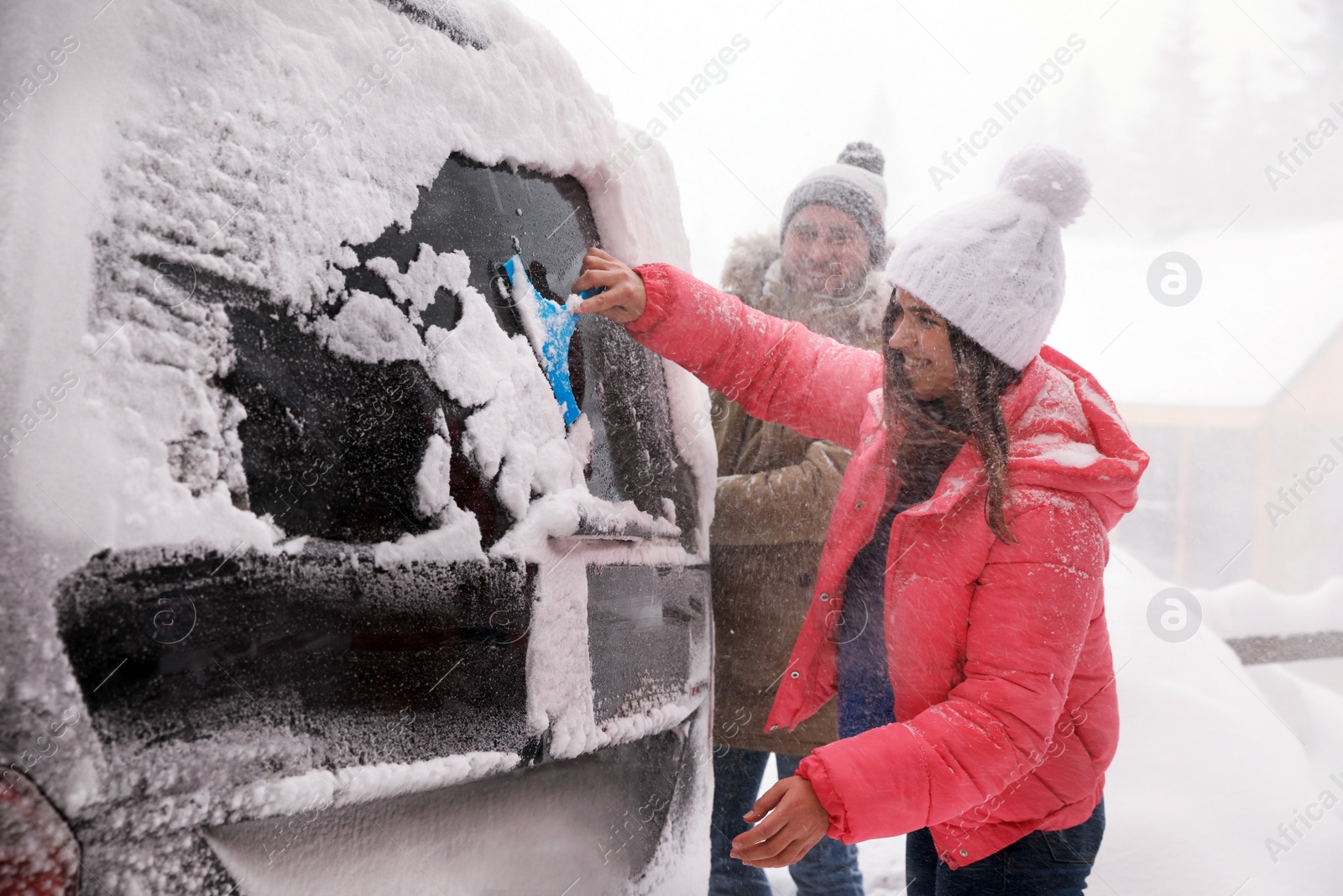 Photo of Man cleaning snow from car outdoors on winter day