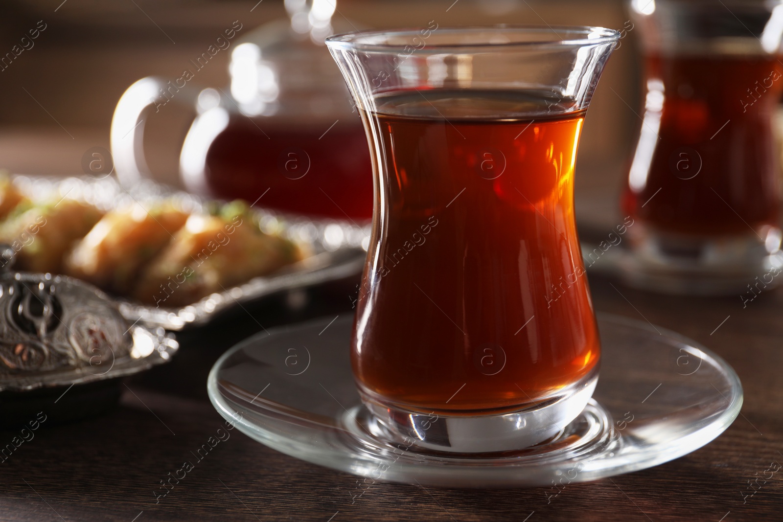 Photo of Traditional Turkish tea in glass on wooden table, closeup