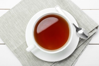 Aromatic tea in cup and spoon on white wooden table, top view