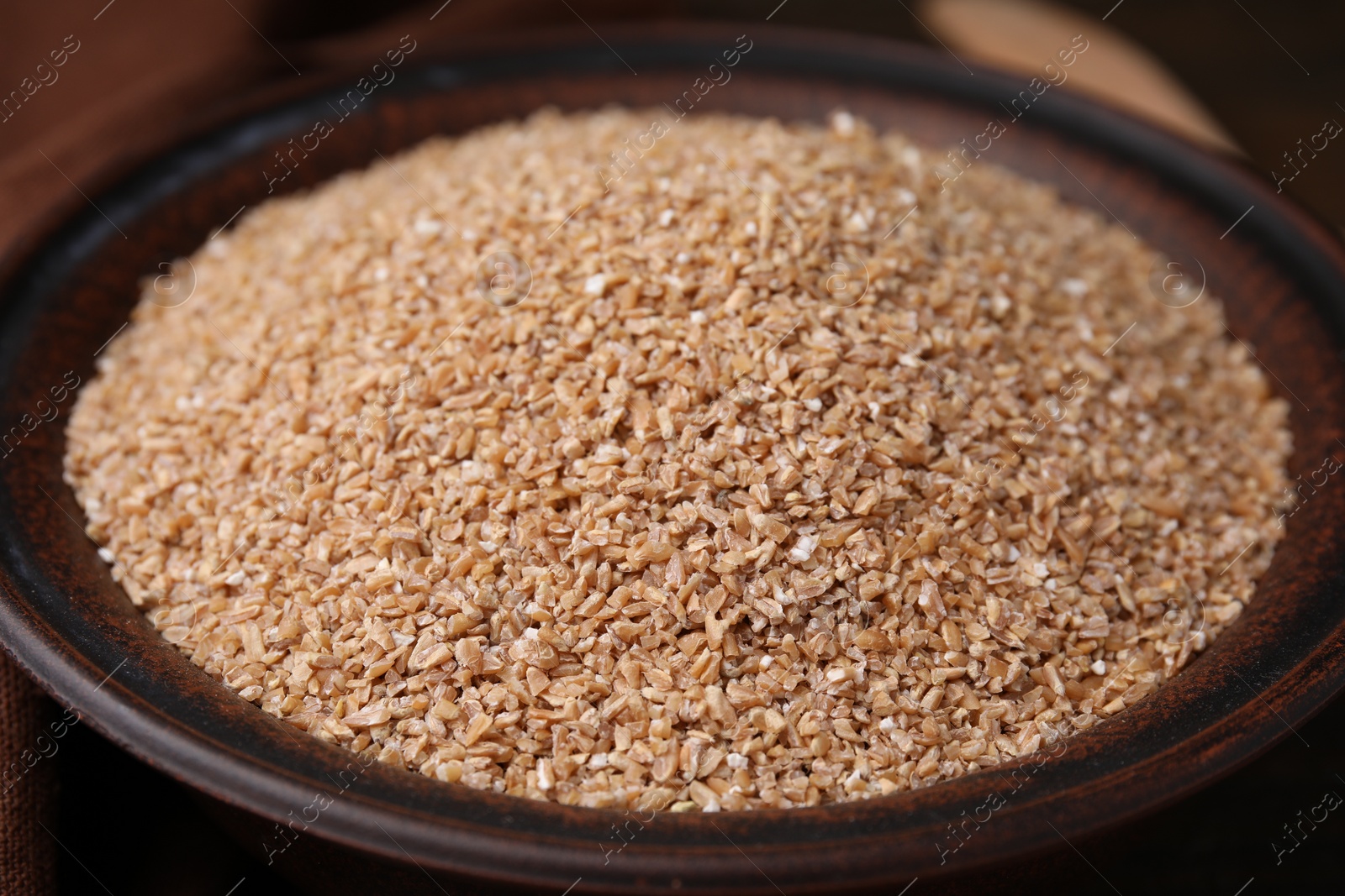 Photo of Dry wheat groats in bowl, closeup view