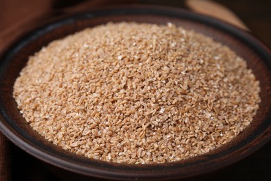 Photo of Dry wheat groats in bowl, closeup view