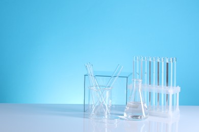 Photo of Laboratory analysis. Different glassware on table against light blue background, space for text