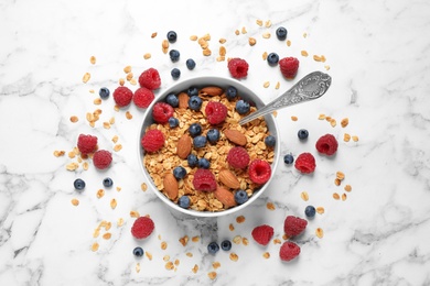 Photo of Tasty homemade granola with berries on white marble table, top view. Healthy breakfast
