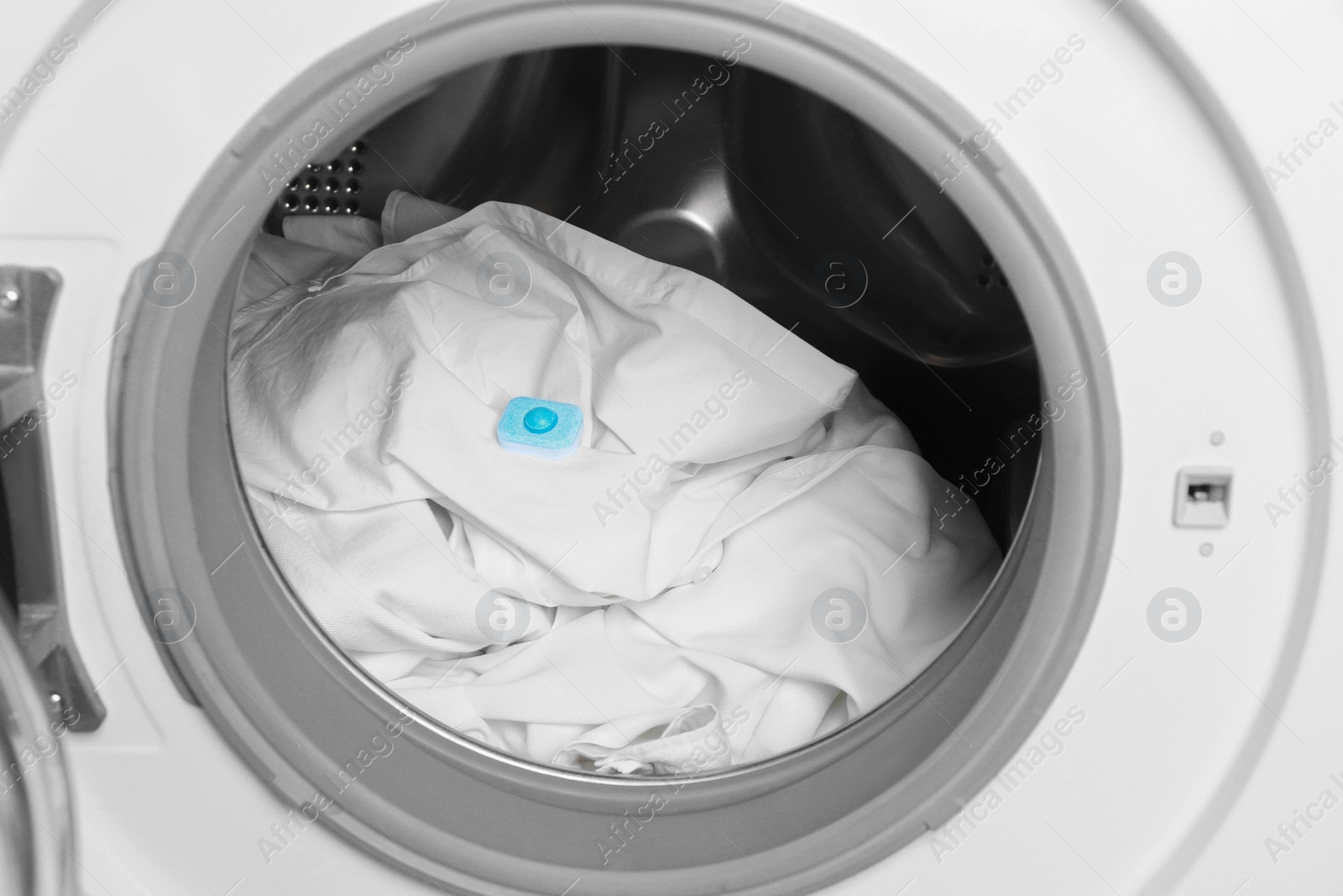 Photo of Water softener tablet on clothes in washing machine