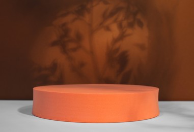 Photo of Orange round stand on white table. Stylish presentation for product