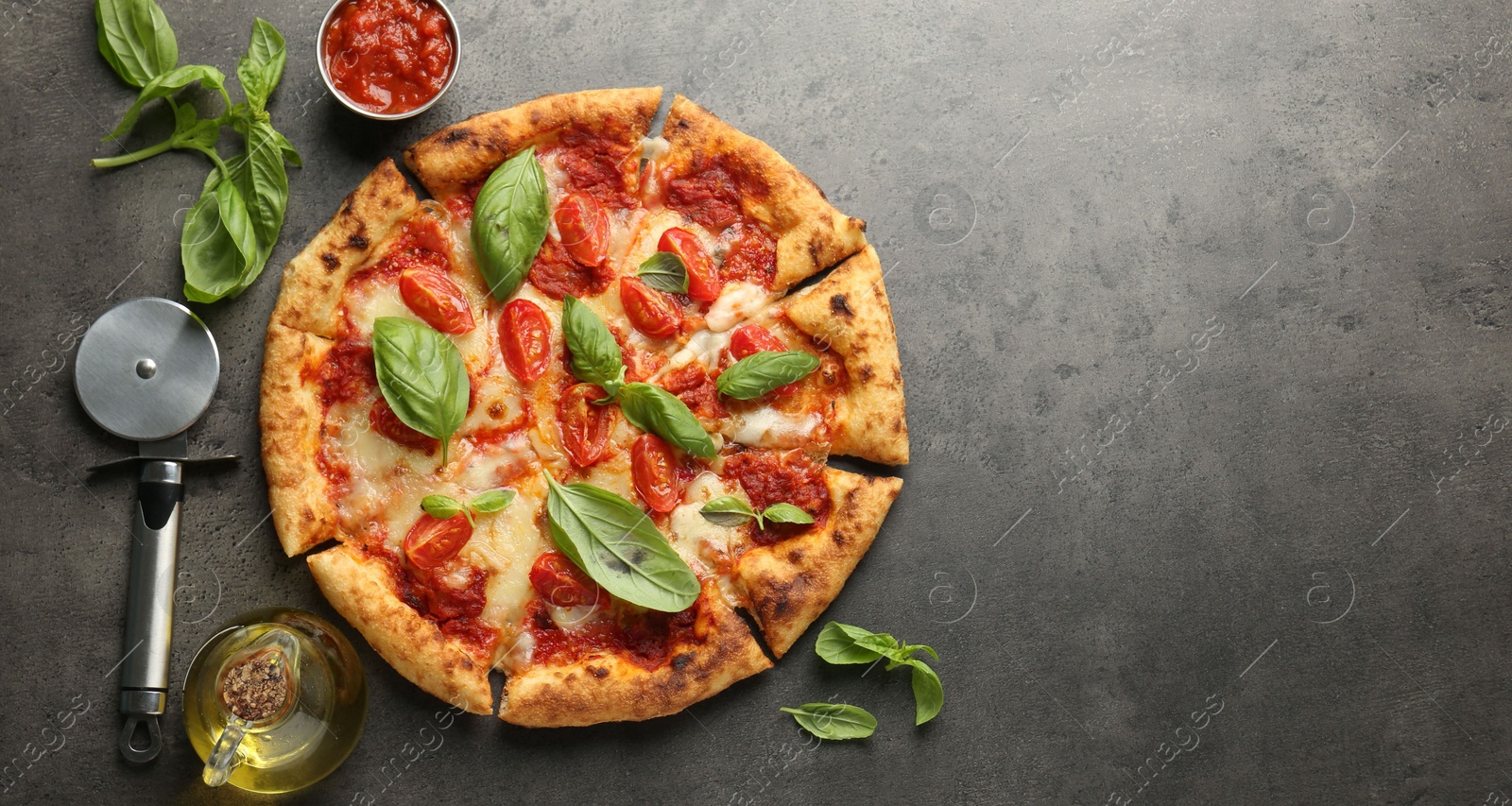 Photo of Delicious Margherita pizza, ingredients and cutter on grey table, top view. Space for text