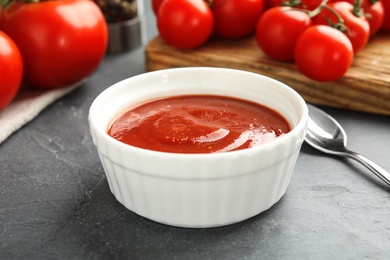 Photo of Composition with bowl of tomato sauce on grey table