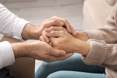 Photo of Man holding woman's hands indoors, closeup. Concept of support and help