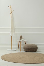 Photo of Simple hall interior with pouf, clothes rack and decor elements. Space for text
