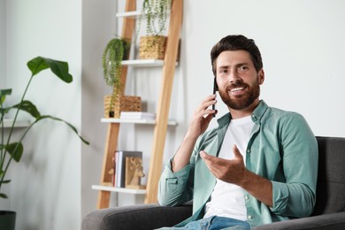 Handsome man talking on phone at home, space for text