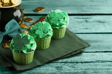 St. Patrick's day. Tasty cupcakes with clover leaf toppers and cream on green wooden table. Space for text