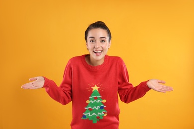 Photo of Surprised young woman in Christmas sweater on yellow background