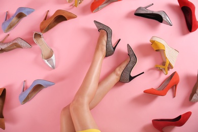 Photo of Woman and different high heel shoes on pink background, top view
