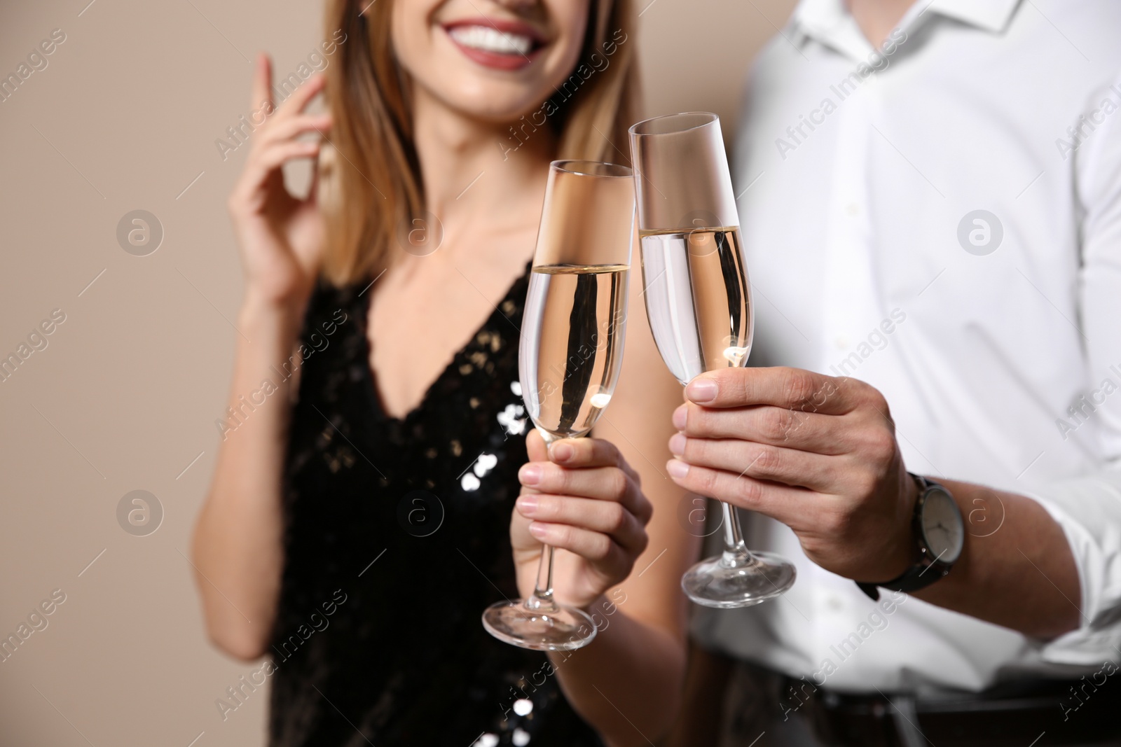 Photo of Happy couple with glasses of champagne on color background, closeup