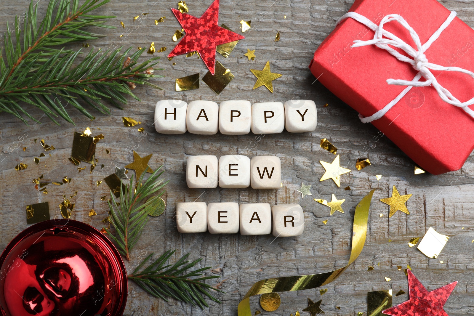 Photo of Phrase Happy New Year made of cubes and festive decor on wooden background, flat lay