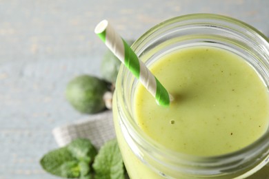 Photo of Fresh feijoa smoothie in mason jar on grey table, closeup. Space for text