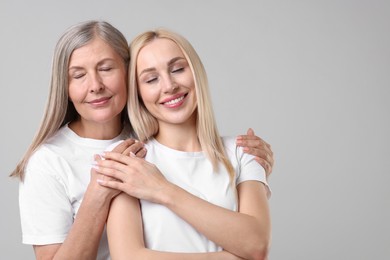 Photo of Family portrait of young woman and her mother on light grey background. Space for text