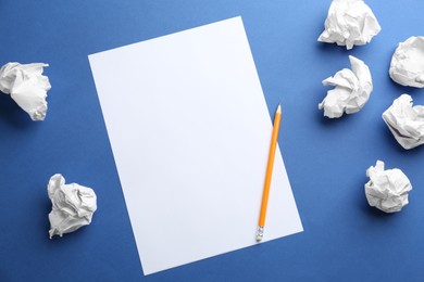 Photo of Blank sheet, pencil and crumpled paper balls on blue background, flat lay. Space for text