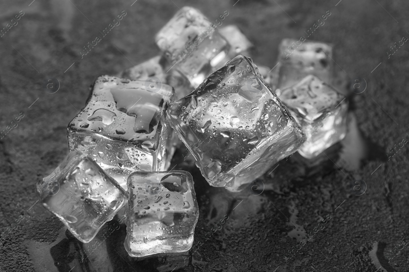 Photo of Crystal clear ice cubes with water drops on grey table, closeup