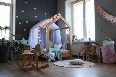 Stylish child room interior with house bed and different toys