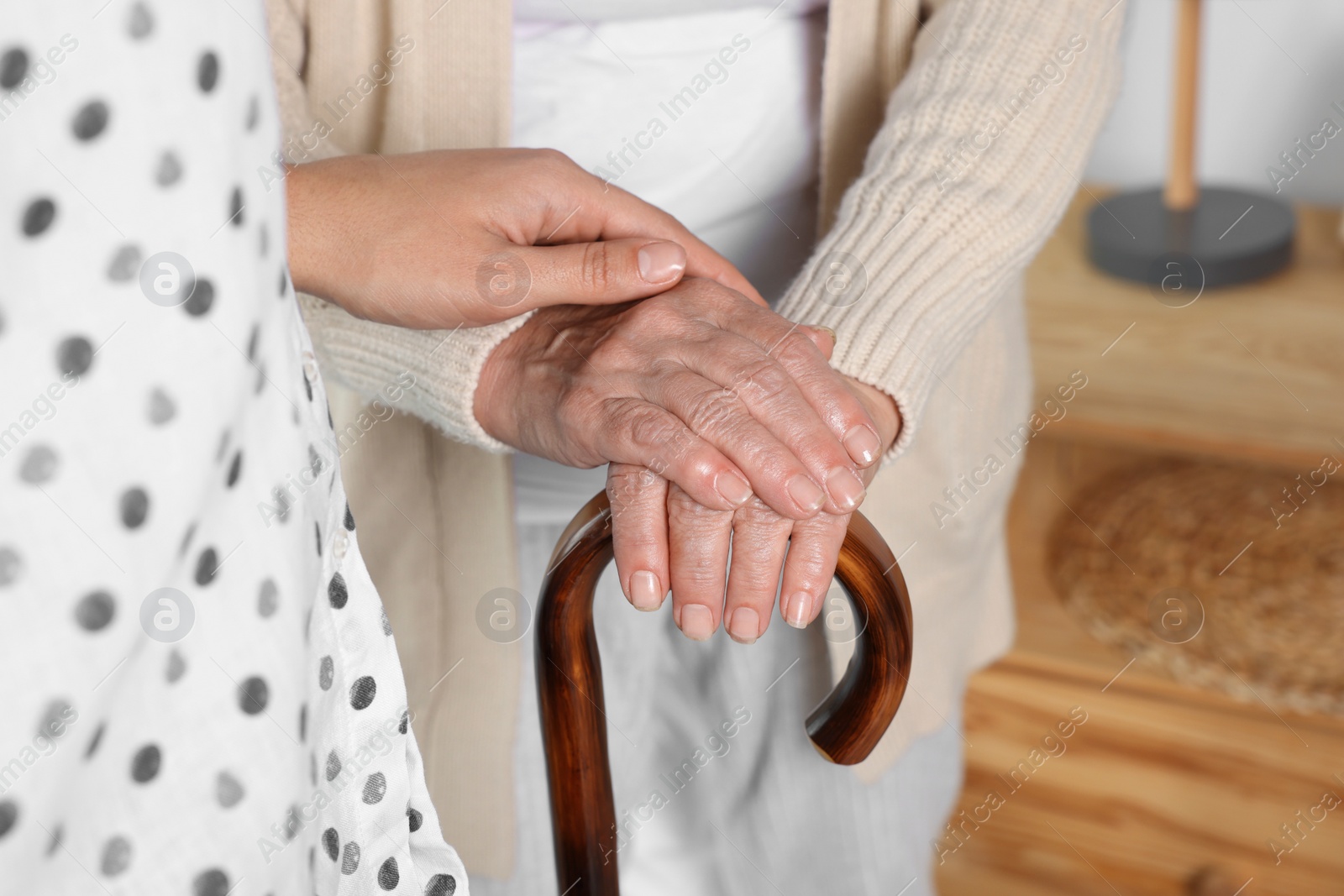 Photo of Caregiver and elderly woman with walking cane at home, closeup