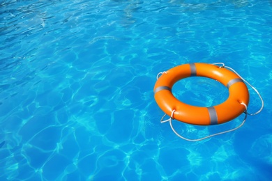 Photo of Lifebuoy floating in swimming pool on sunny day. Space for text