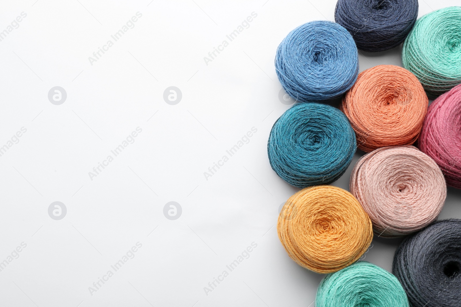 Photo of Clews of colorful knitting threads on white background, top view