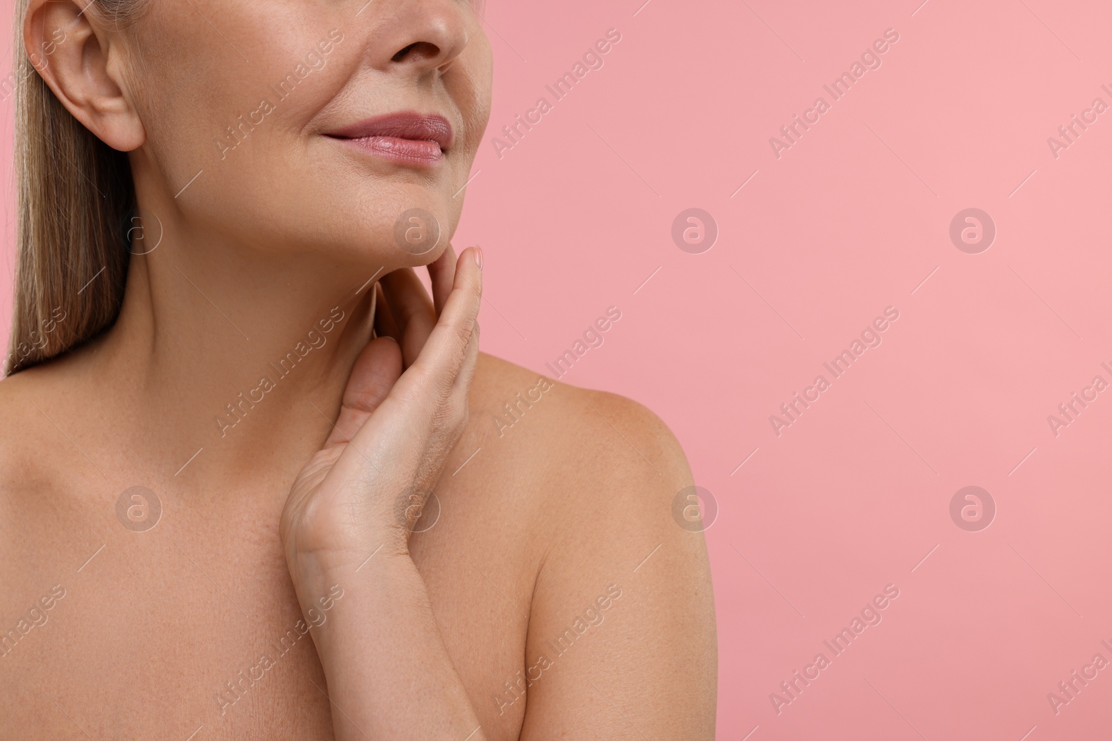 Photo of Mature woman touching her neck on pink background, closeup. Space for text