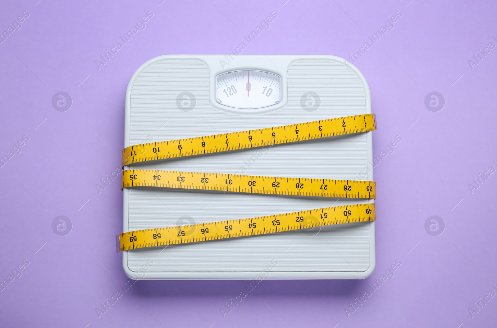 Photo of Scales and measuring tape on violet background, top view