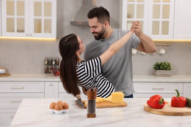 Happy lovely couple dancing together while cooking in kitchen