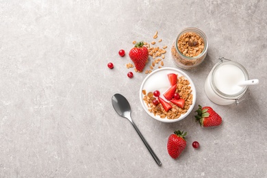 Photo of Tasty breakfast with yogurt, berries and granola on gray table, top view