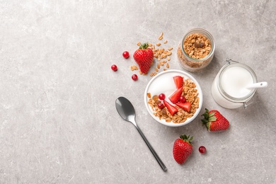 Tasty breakfast with yogurt, berries and granola on gray table, top view