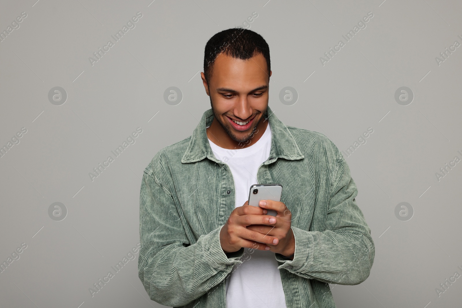 Photo of Smiling African American man with smartphone light grey background. Space for text