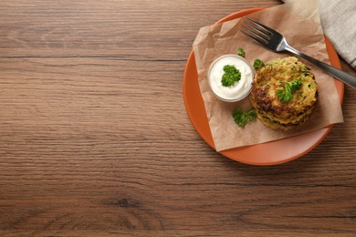 Photo of Delicious zucchini pancakes served on wooden table, flat lay. Space for text