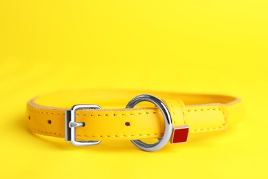 Photo of Leather dog collar on yellow background, closeup. Space for text