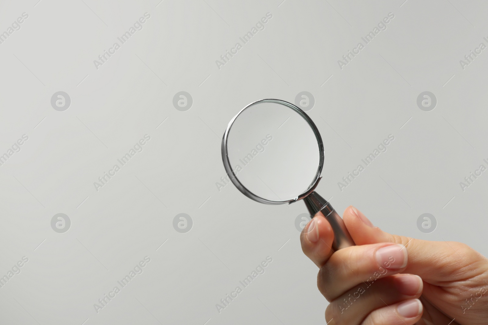 Photo of Woman holding magnifying glass on white background, closeup. Space for text