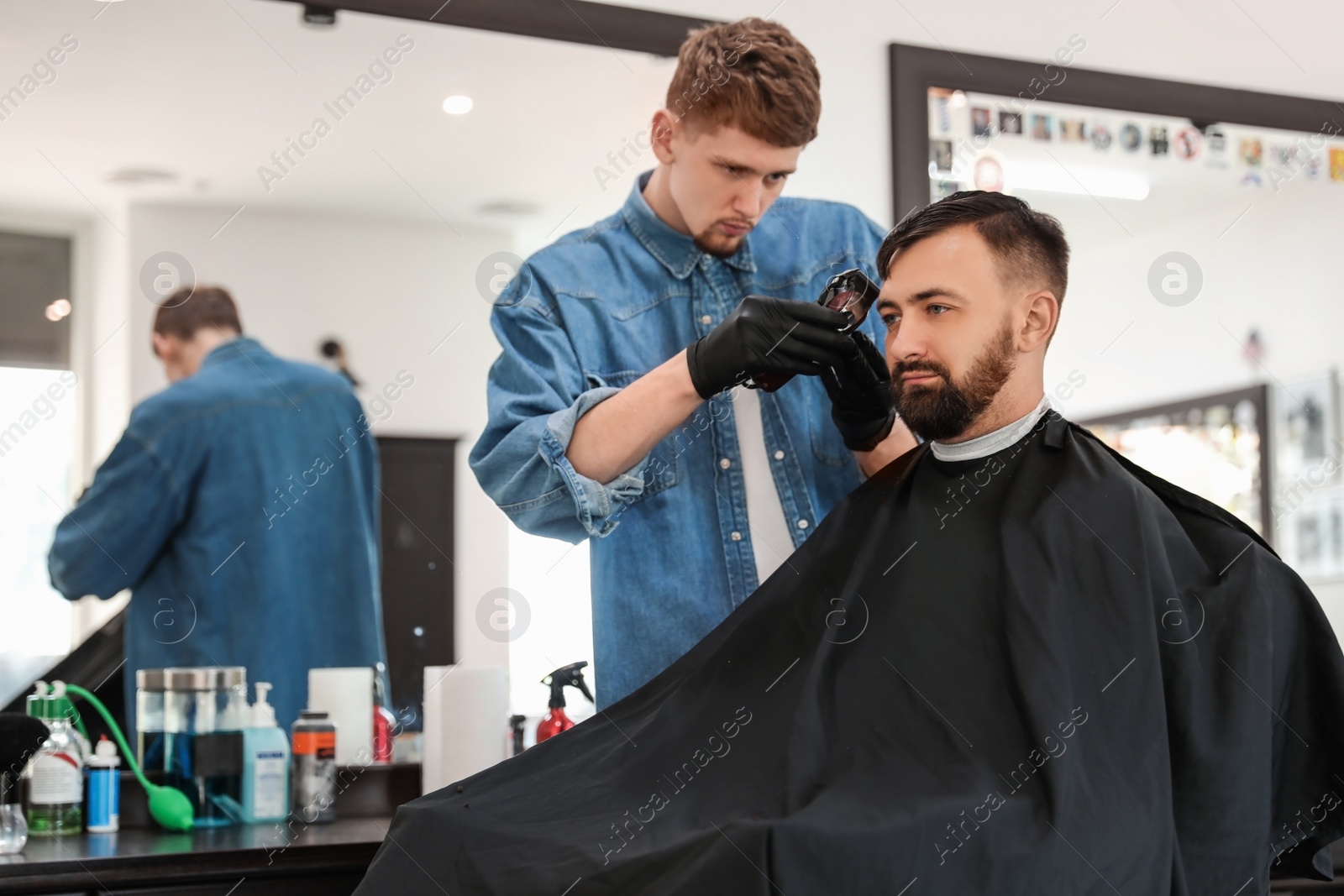 Photo of Professional barber working with client in hairdressing salon. Hipster fashion