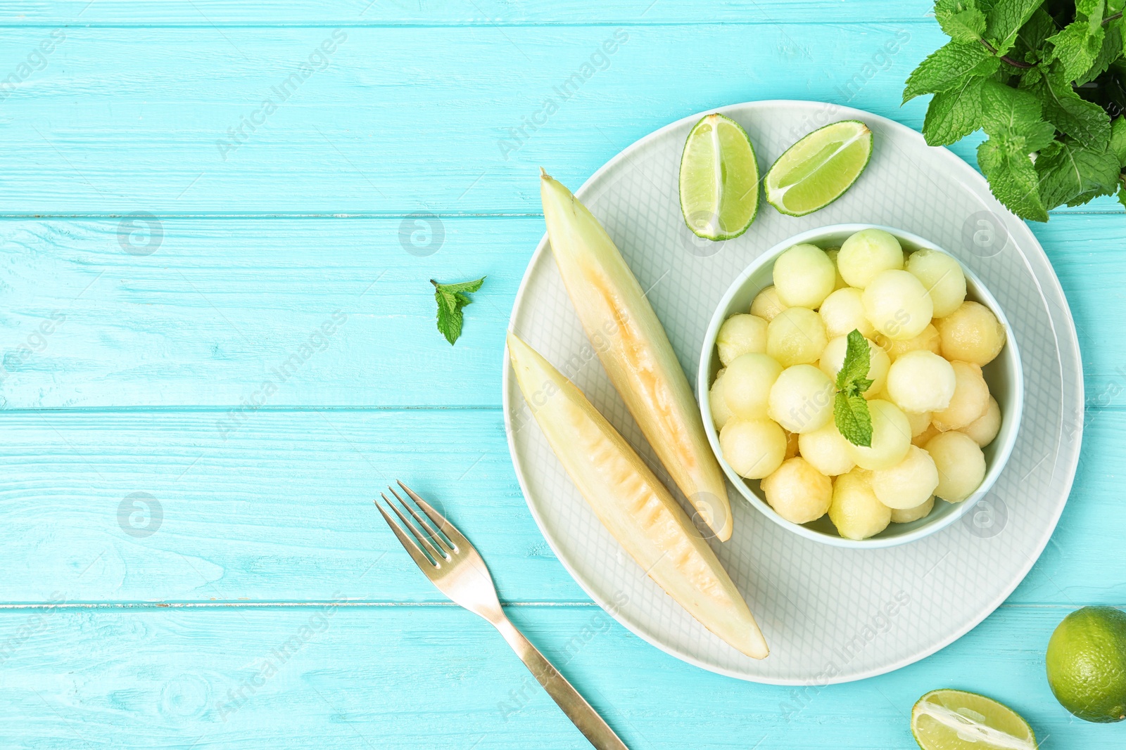 Photo of Melon balls with mint and lime on light blue wooden table, flat lay. Space for text