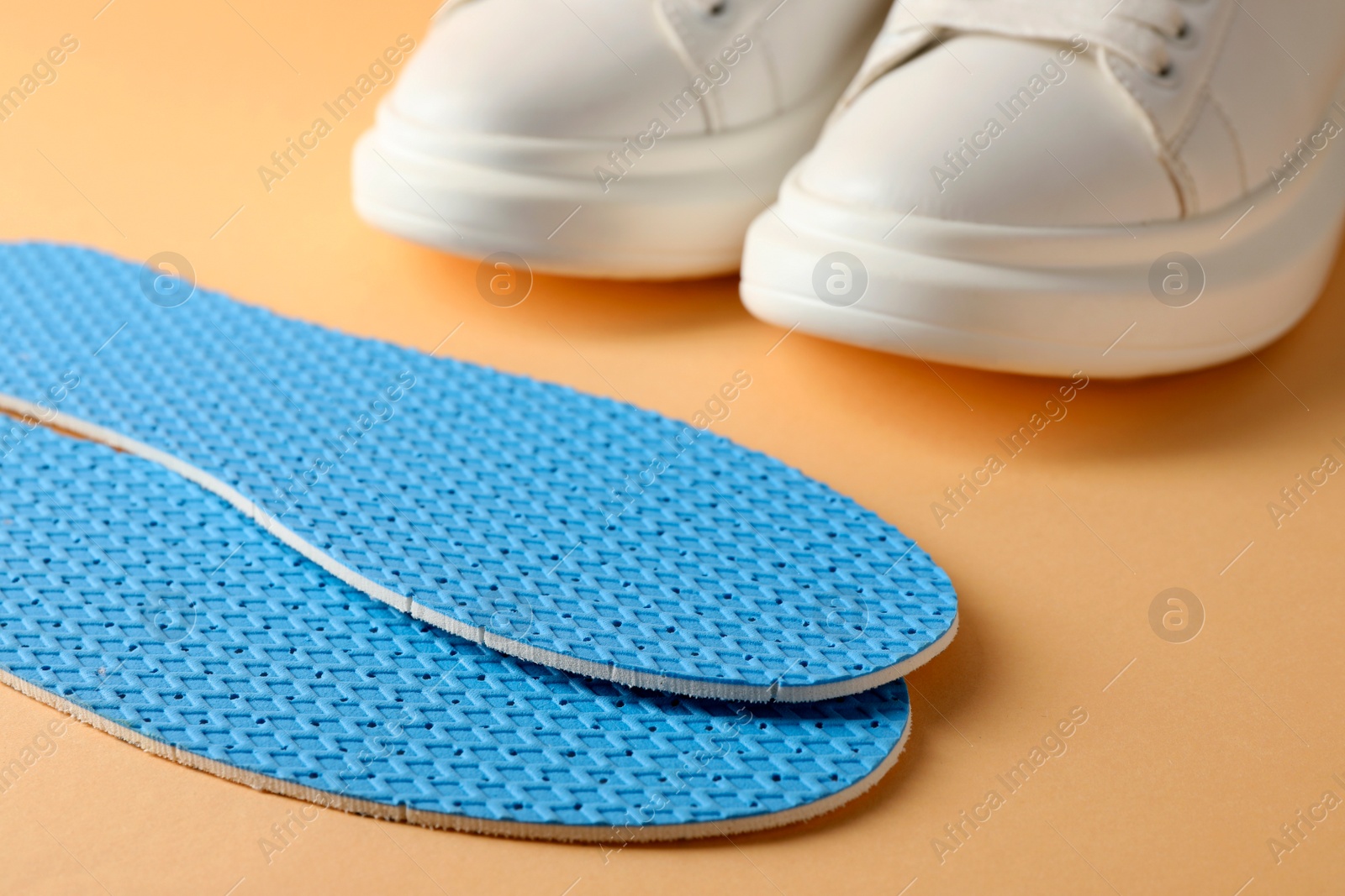 Photo of Pair of insoles and shoes on pale orange background