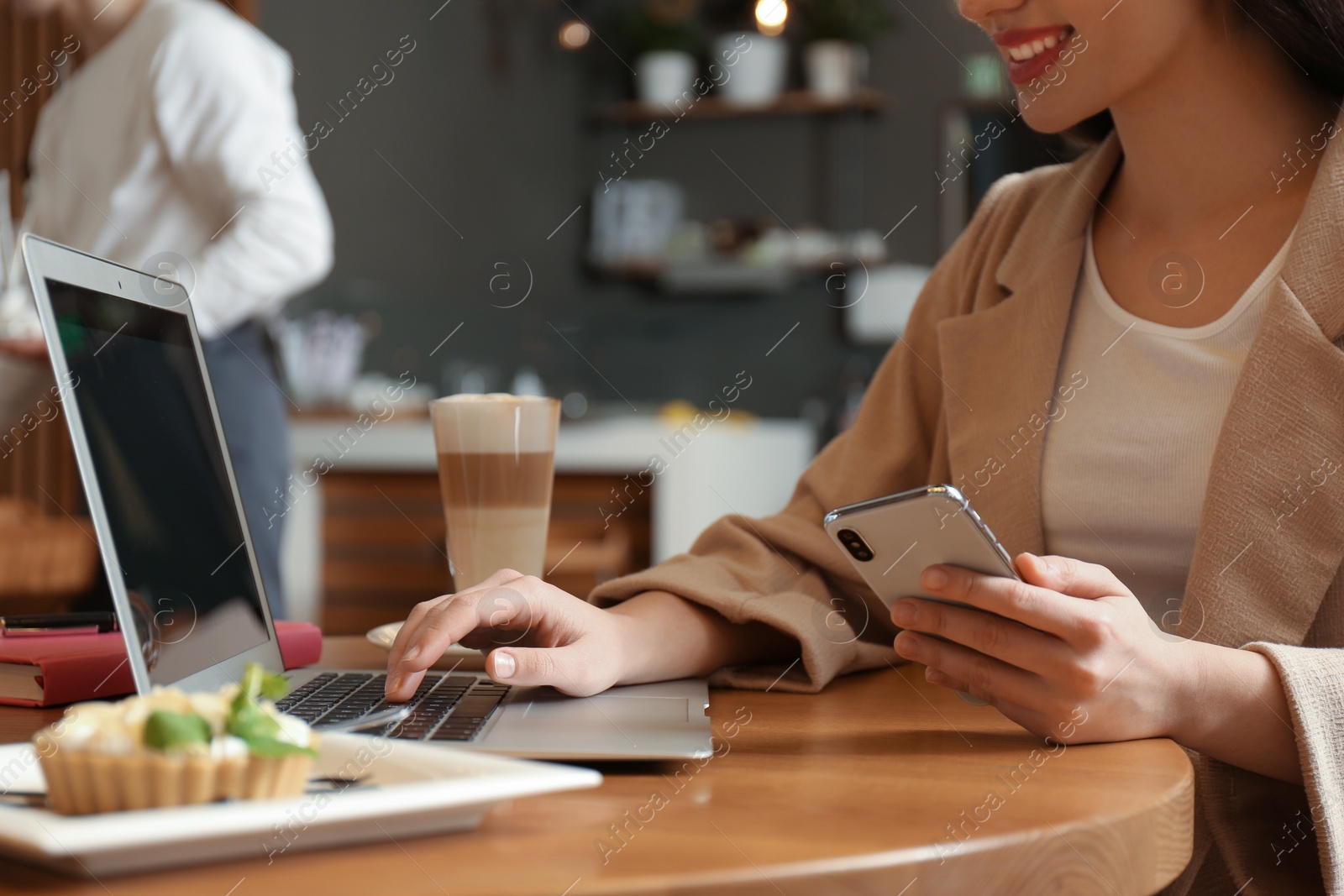 Photo of Blogger with smartphone and laptop in cafe, closeup