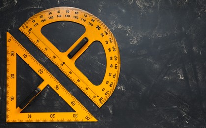 Photo of Protractor and triangle ruler on blackboard, flat lay. Space for text