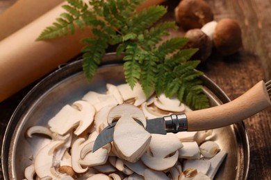 Photo of Cut mushrooms and knife on wooden table, closeup