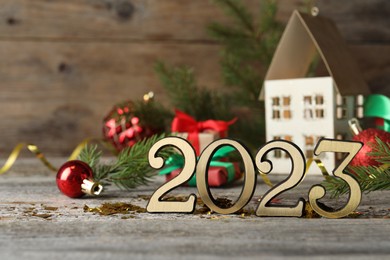 Photo of Number 2023 and festive decor on wooden table, space for text. Happy New Year