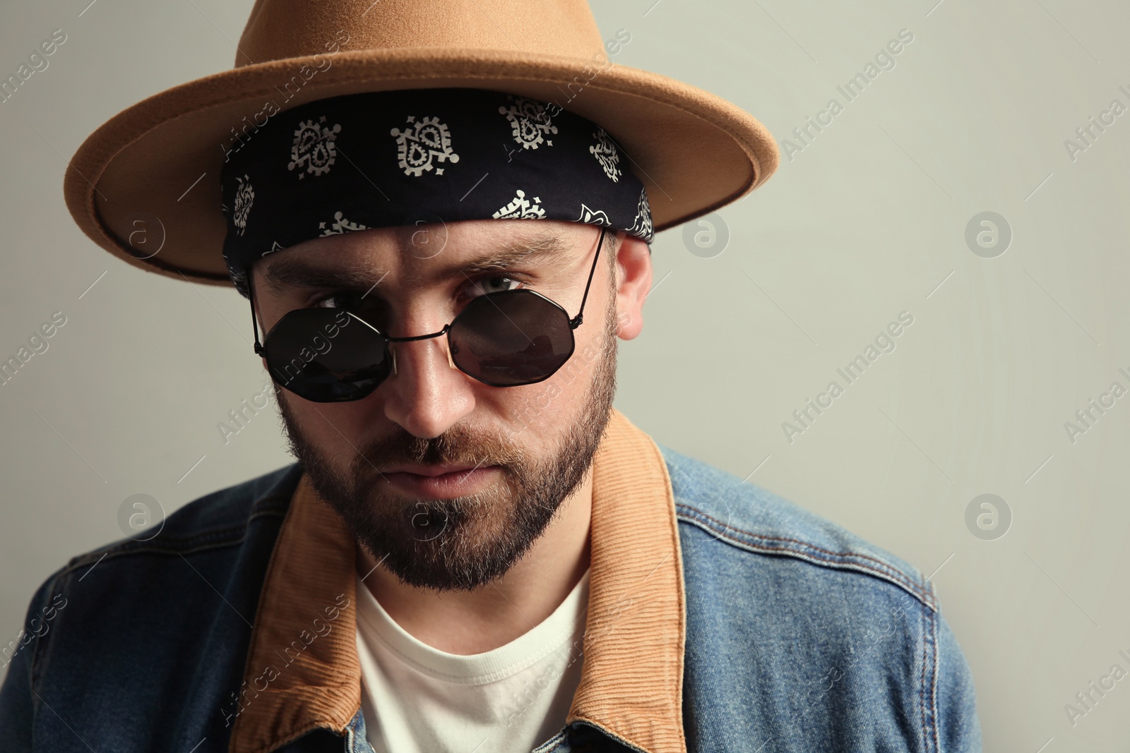 Photo of Fashionable young man in stylish outfit with bandana on grey background