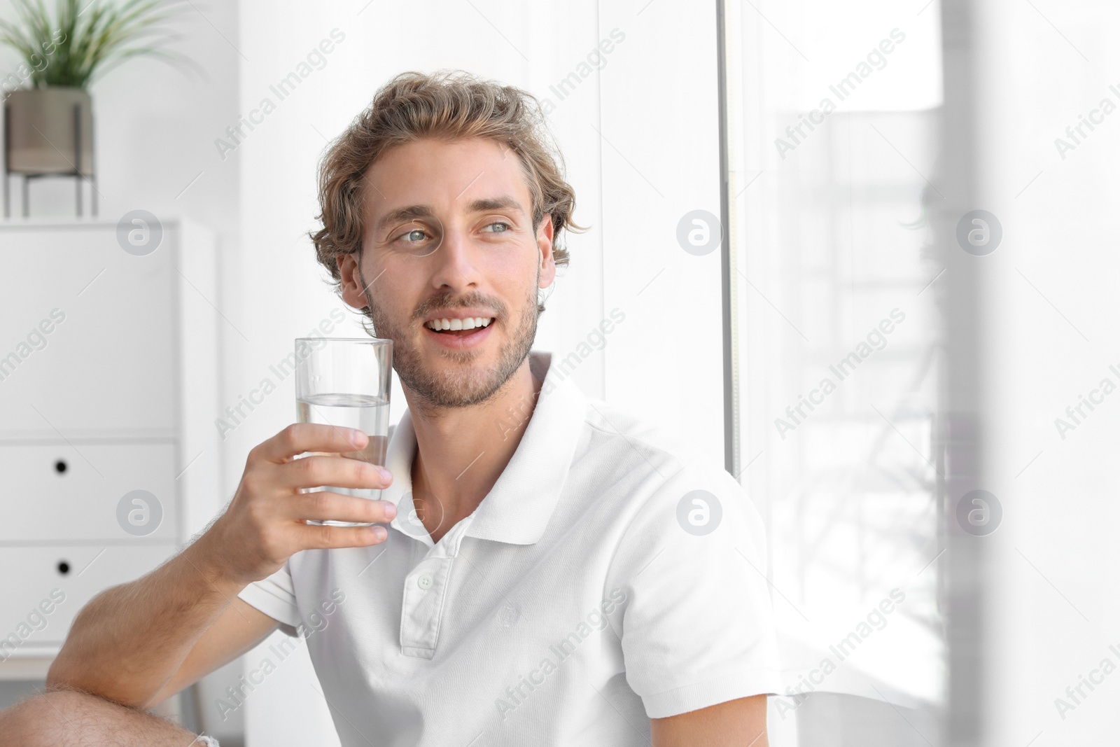 Photo of Young man holding glass of clean water indoors