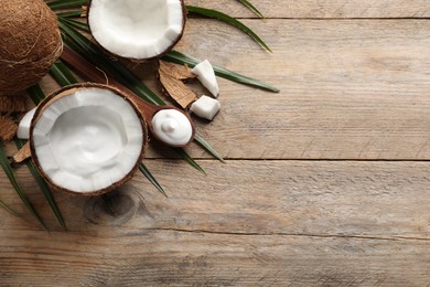 Photo of Ripe coconut and cream on wooden table, flat lay. Space for text