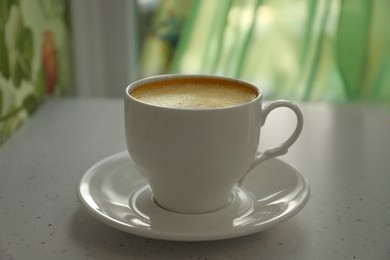 Photo of Cup of delicious aromatic coffee on white table indoors