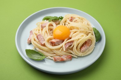 Photo of Delicious pasta Carbonara with egg yolk on light green background, closeup