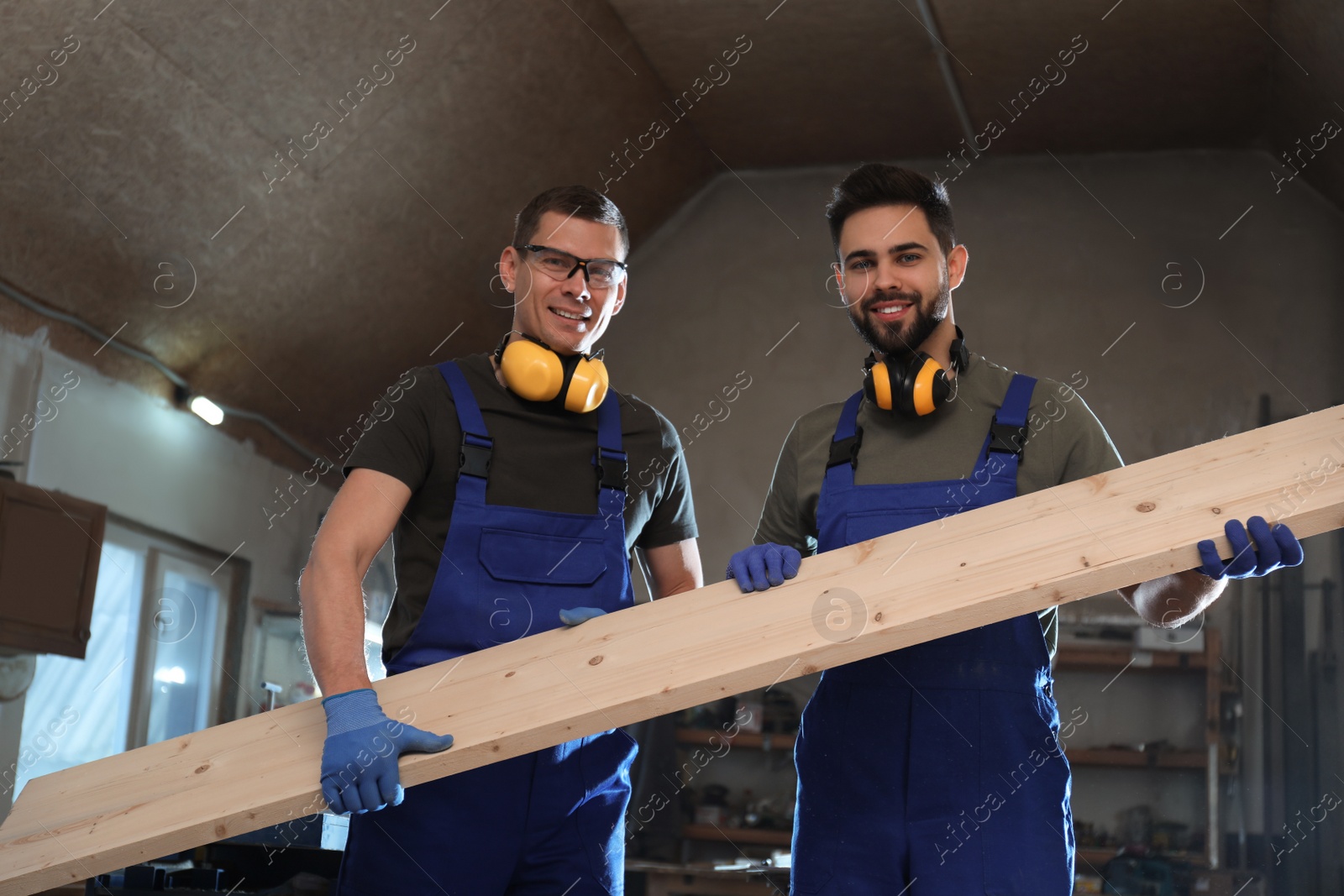 Photo of Professional carpenters with large wooden board in workshop	