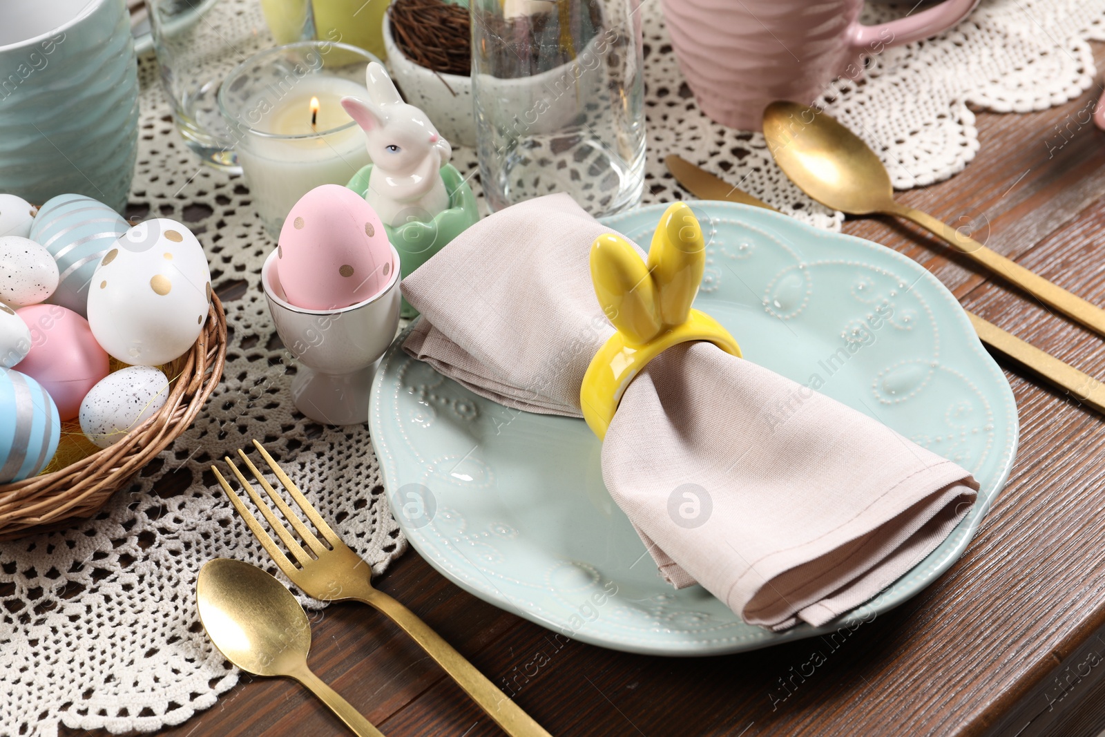 Photo of Festive table setting with napkin ring in shape of bunny ears, closeup. Easter celebration